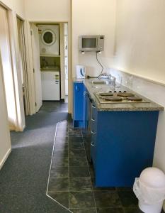 uma cozinha com uma ilha azul e um lavatório em Bay Road Motels em Haast