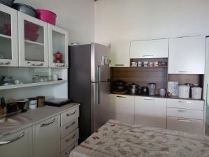 a kitchen with white cabinets and a refrigerator at Aluguel de Quarto em uma casa in Cavalcante