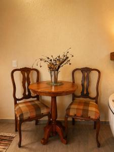 a table with two chairs and a vase with flowers at Refúgios de Mauá - Chalé Jardins de Maria in Visconde De Maua