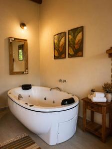 a white bath tub in a bathroom with a mirror at Refúgios de Mauá - Chalé Jardins de Maria in Visconde De Maua