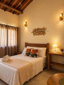 a bedroom with a bed with white sheets and a table at Refúgios de Mauá - Chalé Jardins de Maria in Visconde De Maua +2 photos