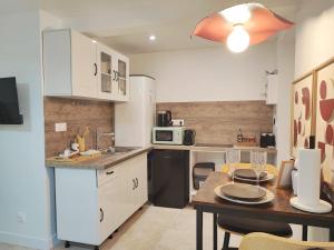 a kitchen with white cabinets and a dining table at La Suite Bohème Émeraude in Évreux