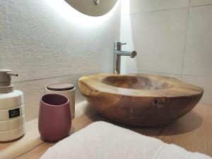 a bathroom with a wooden bowl sink in a bathroom at La Suite Bohème Émeraude in Évreux