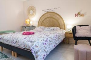 a bedroom with a bed with a blanket and a chair at Jolie maison cosy in Saint-Uze