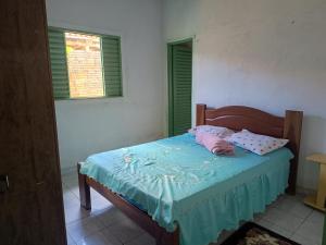 a bedroom with a bed with a blue blanket and two windows at Aluguel de Quarto em uma casa in Cavalcante