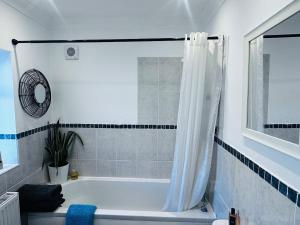 a bathroom with a bath tub with a shower curtain at Palm Valley Villa in Poole +86 photos