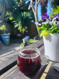 a drink in a cup on a wooden table with flowers at Palm Valley Villa in Poole