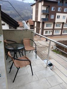 a cat sitting on the ledge of a balcony with chairs at Apartman Danica in Foča