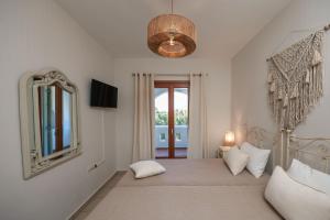 a bedroom with a bed with a mirror and a window at Villa Alyko in Aliko Beach