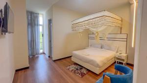 a bedroom with a white bed and a blue chair at Mamush Hotel in Ārba Minchʼ