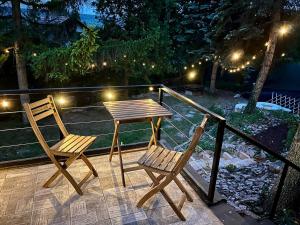 two chairs and a table on a deck at night at Hegyi Kuckó Vendégház - Forest Hideaway with Jacuzzi in Biatorbágy +3 photos