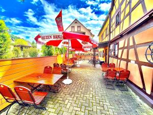 a patio with red chairs and tables and umbrellas at Gasthaus Goldener Anker in Gemünden