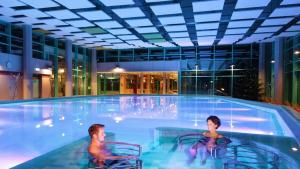 two men sitting in chairs in a swimming pool at CariSSA Ferienwohnung - mit THERMEplus in Bad Bevensen