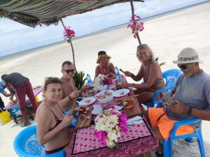 a group of people sitting at a table on the beach at Funzi Beach Resturant in Funzi