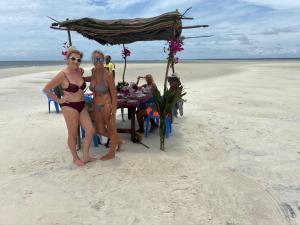 two women in bathing suits on the beach with a table on the beach at Funzi Beach Resturant in Funzi