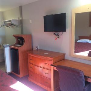 a room with a bedroom with a dresser and a mirror at Crown Lodge Motel in Oakland