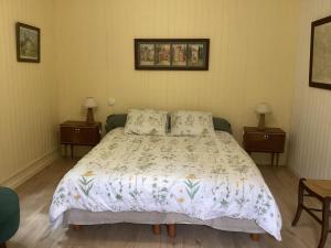 a bed in a bedroom with two tables and two lamps at Cabane de charme in Losse