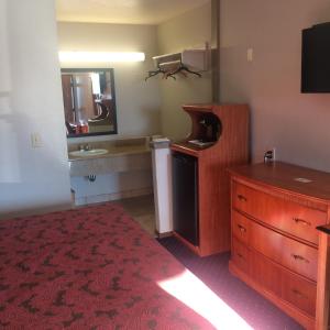 a room with a bed and a dresser and a sink at Crown Lodge Motel in Oakland