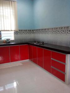 uma cozinha com armários vermelhos e um balcão preto em Homestay Seri Nipah Perlis em Kangar