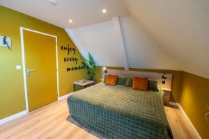 a bedroom with a bed and a yellow wall at Hotel Onder De Linden in Roden