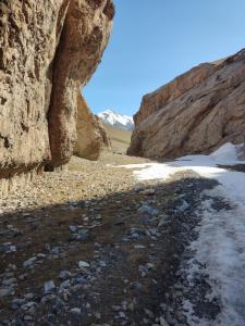 a rocky beach next to a large rock cliff at Nice Hostel in Sary-Mogul