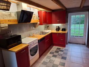 a kitchen with red cabinets and a sink and a stove at Kazh bihan in Guissény +40 photos