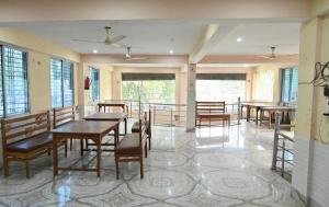 a dining room with tables and chairs and windows at Chouhan Hotel in Katihār