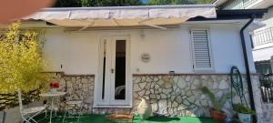 a white house with a stone wall and a door at La Casetta in Monteforte Irpino
