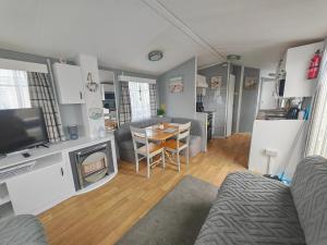 a living room with a couch and a table with a television at 237 Sealands, 6 Birth caravan in Ingoldmells
