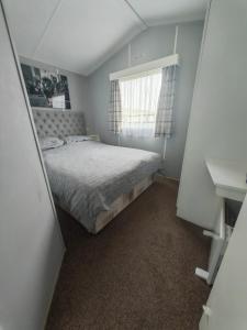 a small bedroom with a bed and a window at 237 Sealands, 6 Birth caravan in Ingoldmells