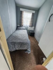 a bed in a small room with a window at 237 Sealands, 6 Birth caravan in Ingoldmells +2 photos