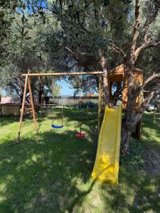 a playground with a tree and a yellow slide at Villa Irabo in Albenga