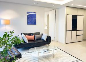 a living room with a black couch and a glass table at Stay in MooD in Busan
