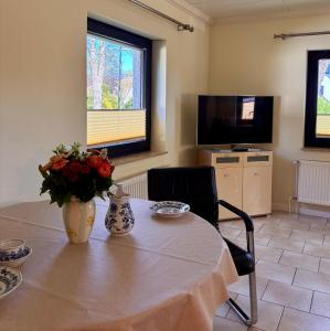 a room with a table with a vase of flowers and a television at Hamburg Living Hub in Pinneberg