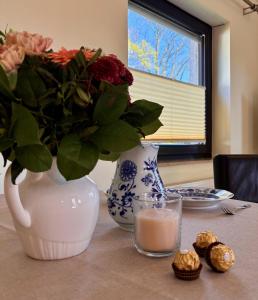 a table with a vase with flowers and a glass of milk at Hamburg Living Hub in Pinneberg
