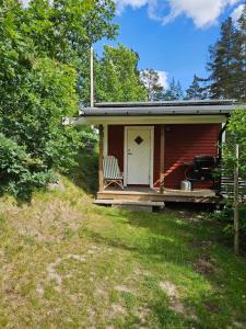 a red cabin with a chair sitting on the porch at Klevenius in Gnesta +10 photos