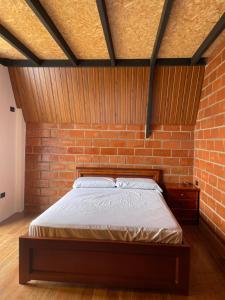 a bedroom with a brick wall and a bed at Refugio de la niebla puyo glamping in Puyo