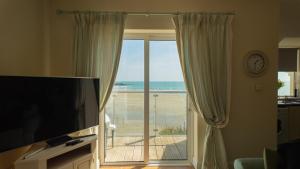 a living room with a television and a view of the ocean at 2 bed Beachfront Apartment Inchydoney Cork in Cork