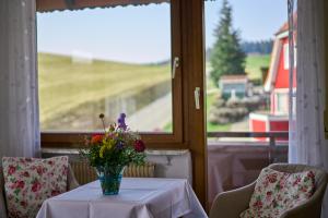 a table with a vase of flowers on it in front of a window at Gasthof ALTE POST-Schwarzwald Plus gratis in Waldachtal +33 photos