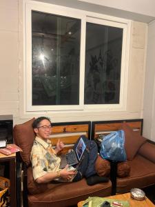 a man sitting on a couch with a laptop at Paila Hostel Lakeside in Pokhara