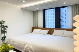 a bedroom with a large white bed and two windows at Stay in MooD in Busan