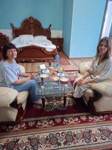 two women sitting in a living room with a coffee table at Ramzan Family Guest House in Samarkand
