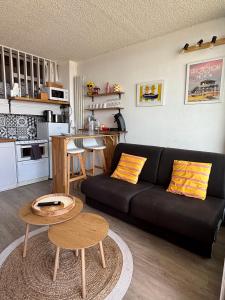 a living room with a black couch and a kitchen at Duplex vue mer et accès plage in Arcachon +12 photos