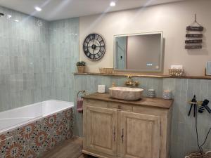 a bathroom with a sink and a tub and a clock at Petit cocon à 5 min du château de Sedan in Sedan +20 photos