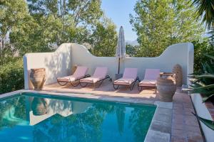 a pool with chairs next to a swimming pool at Villa Camilla in Comares