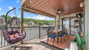a porch with a swing and a table and chairs at Daylight Cove Lakefront Chic in Lake Ozark