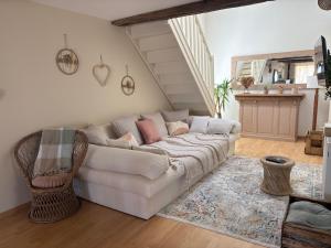 a living room with a white couch and a staircase at Petit cocon à 5 min du château de Sedan in Sedan