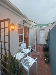 a patio with two white chairs and a lamp at The Muizenberg Muse in Muizenberg