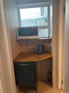 a small desk with a television and a window at The Muizenberg Muse in Muizenberg