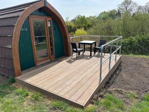 a wooden deck with a table and chairs on a cabin at Rexes Hollow Camping in Yeovil Junction